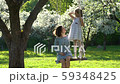Woman and girl in dress spend leisure together in white blooming tree garden 59348425