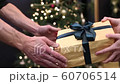 giving a holiday gift near a home Christmas tree a golden box with green ribbons 60706514