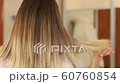 Hair care concept. Blonde woman straightening hair with hair straightener, rear view close-up slow 60760854