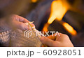 Close up of woman hands knitting by fireplace in warm winter scene. Over the shoulder camera view, girl doing handmade indoors season activity with wool at home. 4k footage. 60928051