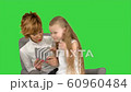 Young mother and her daughter sit together and look at the tablet on a Green Screen, Chroma Key 60960484