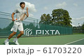 An Asian Tennis Player plays a great shot from the baseline and celebrates game, set and match. 61703220