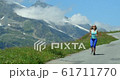 A pretty young blond woman running down a road in the French Alps in summertime. 61711770