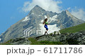 A pretty young blond woman running across the European Alps. 61711786