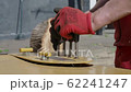The gloved hands of a worker press the levers of an industrial machine. 62241247