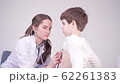 7 year boy with doctor. Physician examines the child with a stethoscope 62261383