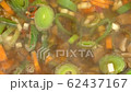 putting fresh cilantro into a boiling vegetable soup top view closeup 4k 62437167