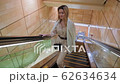 A blonde woman moves on an escalator lift in a subway or shopping mall. On the shoulders of a white 62634634