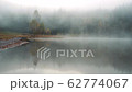 Morning fog in autumn lake landscape. Mountain with trees reflecting in the water 62774067