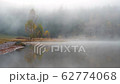 Morning fog in autumn lake landscape. Mountain with trees reflecting in the water 62774068
