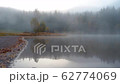 Morning fog in autumn lake landscape. Mountain with trees reflecting in the water 62774069