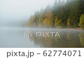 Morning fog in autumn lake landscape. Mountain with trees reflecting in the water 62774071
