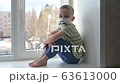 Sad child in protective medical masks lonely sitting near window. Quarantine, staying at home. Slow motion, handheld. 63613000