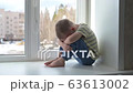 Sad child in protective medical masks lonely sitting near window. Quarantine, staying at home. Slow motion, handheld. 63613002