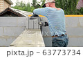 Bricklayer putting down another row of bricks in site 63773734
