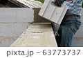 Bricklayer putting down another row of bricks in site 63773737