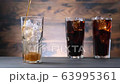 Pouring full glass drink cola with foam, sweet drink with ice and bubbles. On brown wooden background 63995361