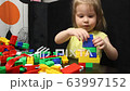 3 years old girl playing with coloured blocks of a constructor. The child develops his thinking skills. Development and education of preschoolers. 63997152