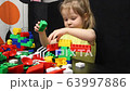 3 years old girl playing with coloured blocks of a constructor. The child develops his thinking skills. Development and education of preschoolers. 63997886