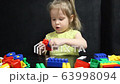 3 years old girl playing with coloured blocks of a constructor. The child develops his thinking skills. Development and education of preschoolers. 63998094