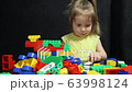 3 years old girl playing with coloured blocks of a constructor. The child develops his thinking skills. Development and education of preschoolers. 63998124