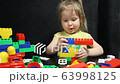 3 years old girl playing with coloured blocks of a constructor. The child develops his thinking skills. Development and education of preschoolers. 63998125