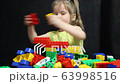 3 years old girl playing with coloured blocks of a constructor. The child develops his thinking skills. Development and education of preschoolers. 63998516