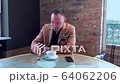 handsome guy drinks big coffee alone in a cafe 64062206