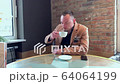 handsome guy drinks big coffee alone in a cafe 64064199