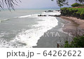 Aerial static view of evening ocean surface, calm waves rolling at rocky shore. Amazing high cliffs above the ocean and Uluwatu temple on the top. Bali, Indonesia 64262622