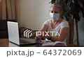 Coronavirus self isolation woman with medical mask spraying antibacterial gel  64372069