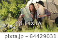 Happy young couple sitting on the nature near tent and campfire, they looking on the map. Forest camping. FullHD Footage. Smiling faces. 64429031
