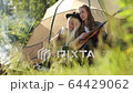 Happy young couple sitting on the nature near tent and campfire, chill, guy playing on a guitar and sings. Forest camping. FullHD Footage. Smiling faces. 64429062