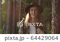 Portrait of handsome young man on a hat looking at camera and smiling at sunset in the forest. Camping. Summer. FullHD video. Travel. 64429064