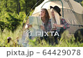 Happy young couple sitting on the nature near tent and campfire, they looking on the map. Forest camping. FullHD Footage. Smiling faces. 64429078