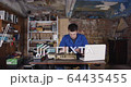 Portrait of young student scientist working and soldering on electronics while watching instructions on laptop in a dirty old garage with brick wall and some old parts in background 4K 64435455