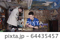 Two young student scientists working in an old dirty workshop with some electronics and passing by details to each other 4K 64435457