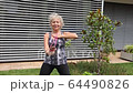 Senior woman is exercising by fitness rubber in her hands. 64490826