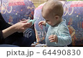 Funny little baby trying to destroy disposable protective face mask. 64490830