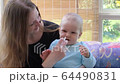 Mother at baby care giving her baby a nasal spray for colds 64490831