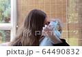 Mom puts on protective mask on her son. 64490832