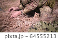 A soldier in a war scout puts dry grass in 64555213