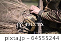 A soldier in a war scout puts dry grass in 64555244