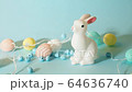 Easter bunny with colorful eggs shaped lights string on pastel color blue background and decor eggs falling down as rain, holiday concept. 64636740