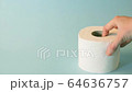 Female hand stacking toilet paper rolls on blue abstract background. Personal hygiene supplies for restroom. 64636757