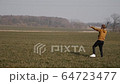 young sports man runs in the field and launches a boomerang into the sky 64723477