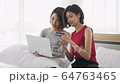 Two Asian women sitting  on bed are using credit cards to shopping online. 64763465