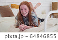 Happy ginger girl smiling on cozy bed at home 64846855