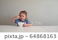 Toddler girl eats healthy food on its own. Independent kid. 64868163