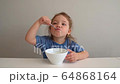 little girl eating oatmeal at a table in the kitchen 64868164